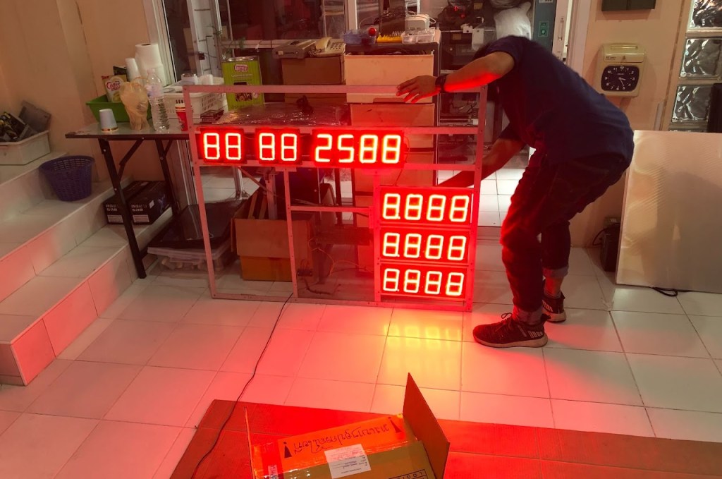 ชายคนหนึ่งกำลังติดตั้งจอ LED แสดงเวลาในห้อง