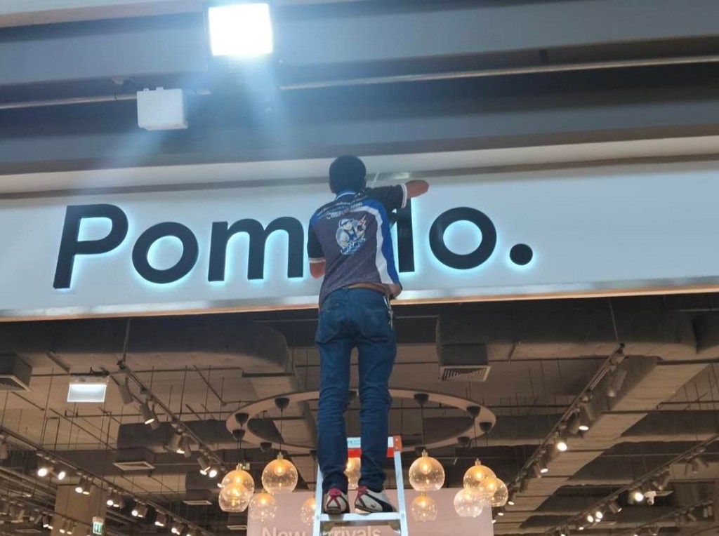 ชายคนหนึ่งกำลังทำความสะอาดป้ายร้าน Pomilo ในห้างสรรพสินค้า