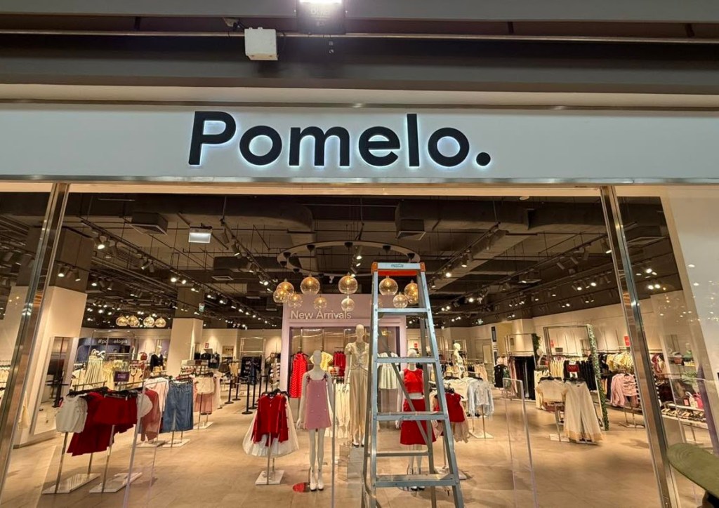 ป้ายชื่อร้าน Pomelo ที่มีบันไดอยู่ด้านหน้าและมุมมองภายในร้านเสื้อผ้า