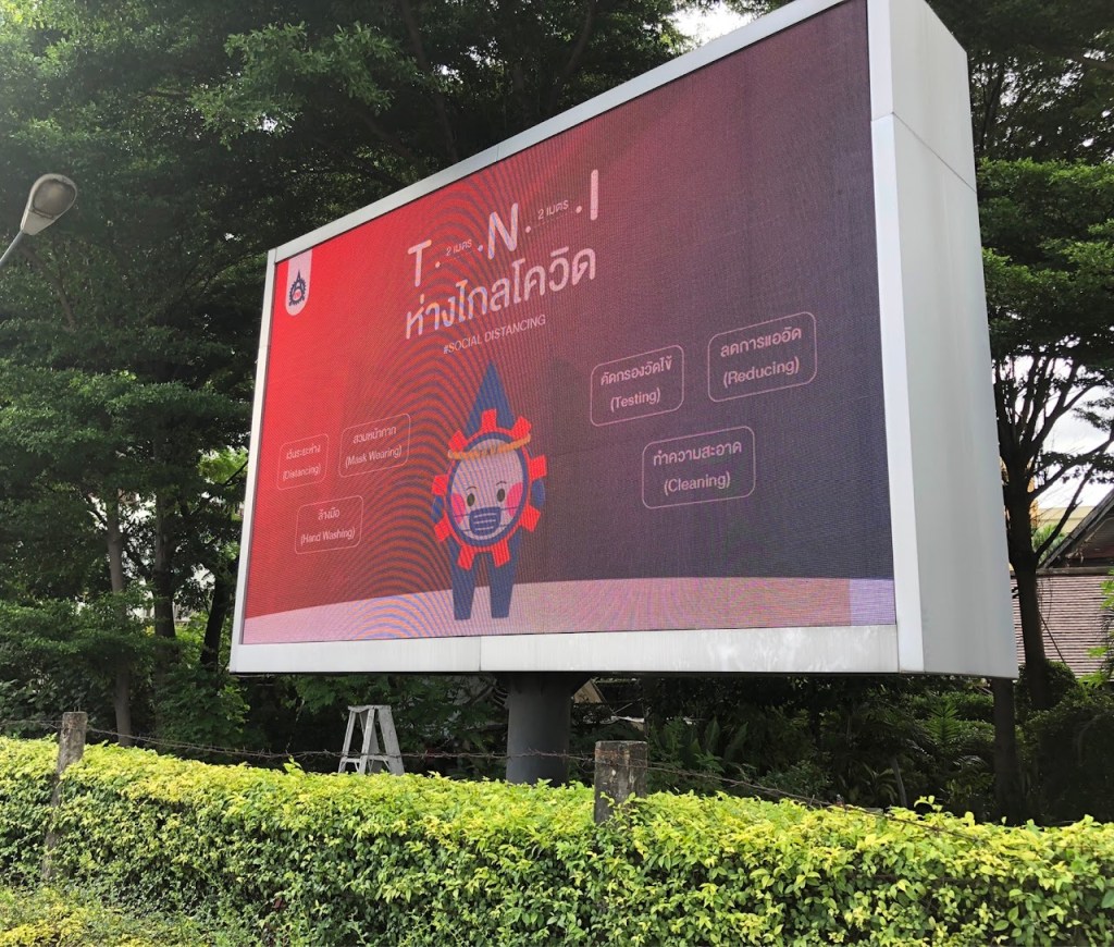 ป้ายโฆษณาขนาดใหญ่เกี่ยวกับการเว้นระยะห่างทางสังคม มีข้อความเกี่ยวกับการสวมหน้ากาก การล้างมือ การทำความสะอาด และการตรวจหาเชื้อ